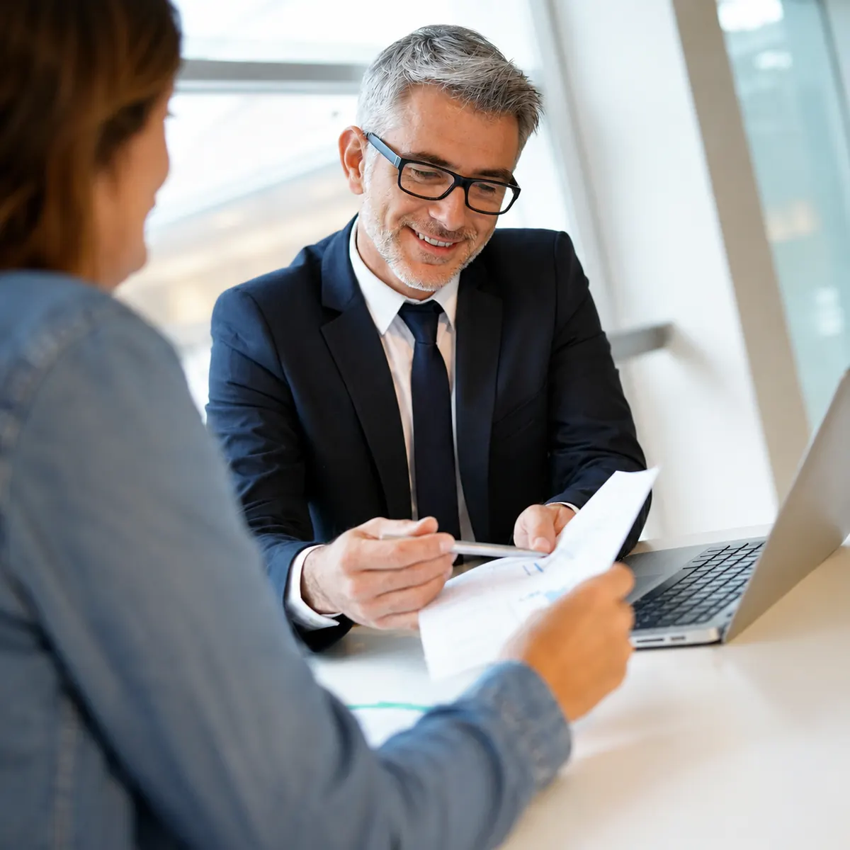 Conseiller remplissant un dossier de financement immobilier avec maquettes de maisons